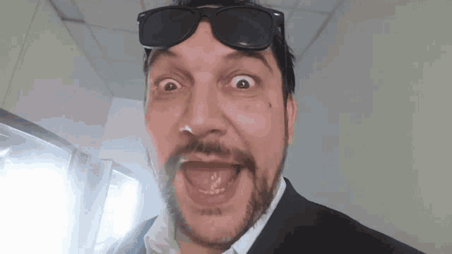 a man in a suit and sunglasses is making a funny face .