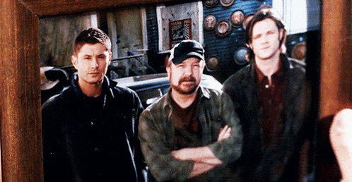a picture of three men standing next to each other with their arms crossed in a wooden frame .