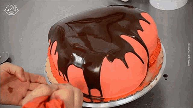 a cake with chocolate dripping on it is being decorated by a person