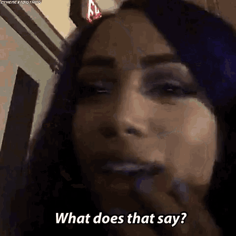 a woman with purple hair is talking to someone and asking what does that say .