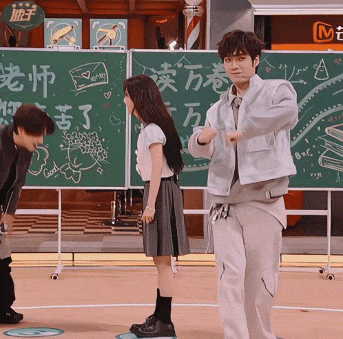 a man and a woman are standing in front of a chalkboard that says good