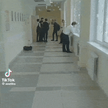 a man is dancing in a hallway while wearing a white shirt and black pants .