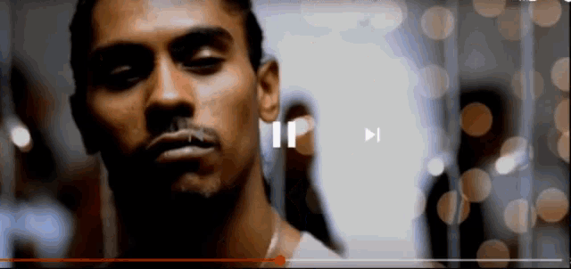a close up of a man 's face with a pause button on the bottom right