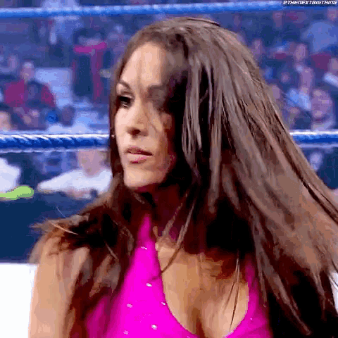a woman in a pink top is in a wrestling ring