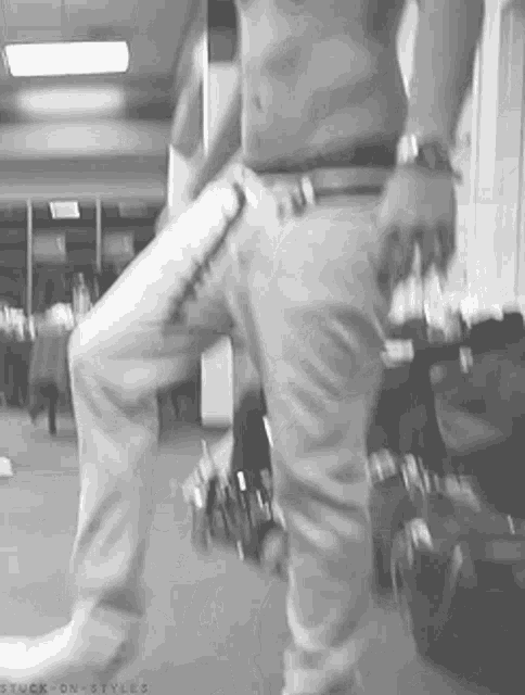 a man without a shirt is walking down a hallway .