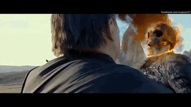 a man is standing in front of a ghost rider with a skull on it 's head