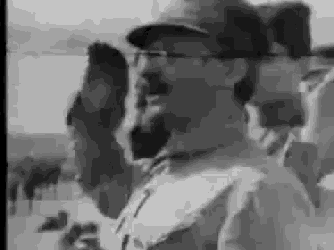 a black and white photo of a man wearing a baseball cap and glasses .