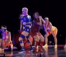a group of people are dancing on a stage in a dark room .
