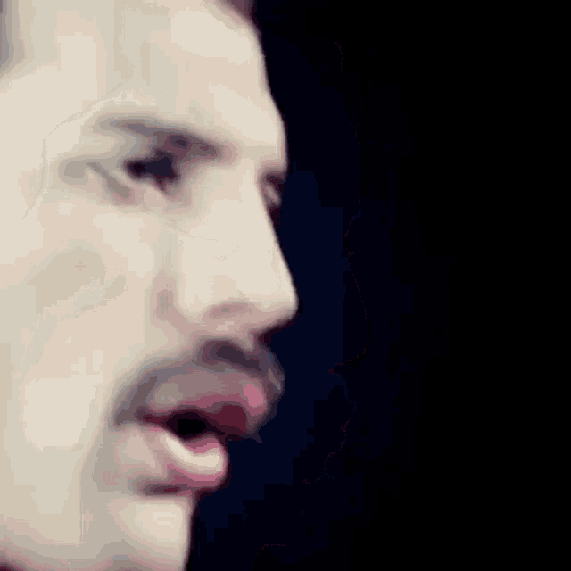 a close up of a man 's face with his mouth open in a dark room .
