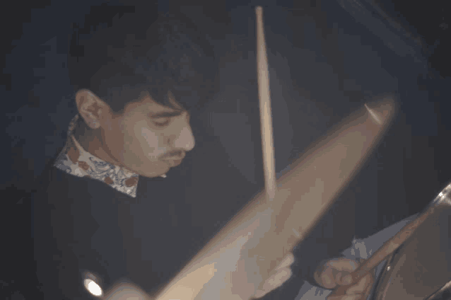 a man in a black shirt is playing a drum set