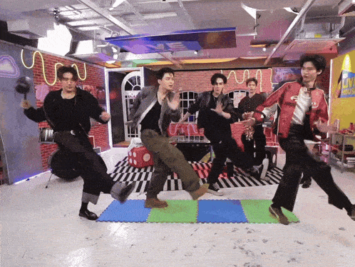 a group of young men are dancing in a room with a live music sign on the wall