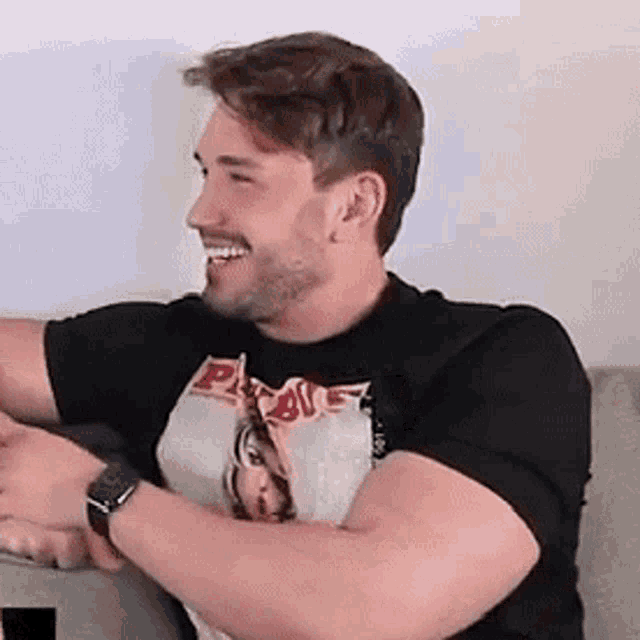 a man with a beard is sitting on a couch and smiling .