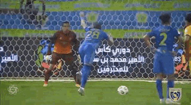 a soccer goalie is falling into the net while a soccer player shoots the ball .