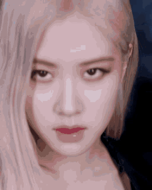a close up of a woman 's face with long blonde hair and pink lipstick .
