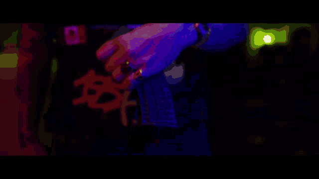 a person wearing a black shirt with chinese writing on it is holding a microphone in a dark room