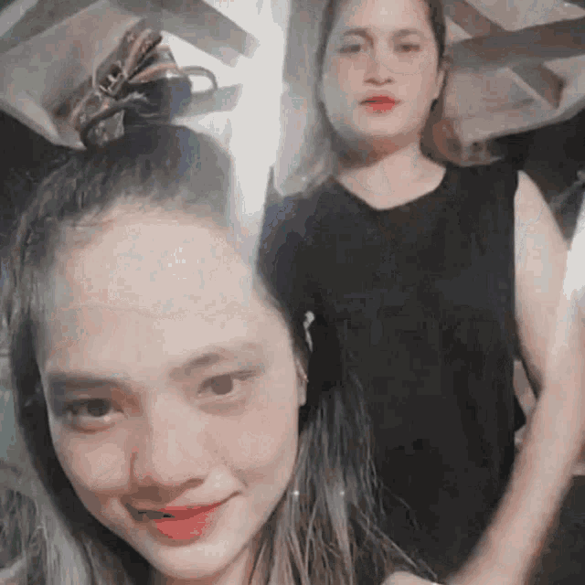 two women are posing for a picture and one has a bun on her hair