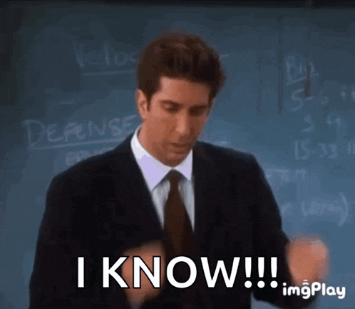 a man in a suit and tie is standing in front of a blackboard and says i know !!!