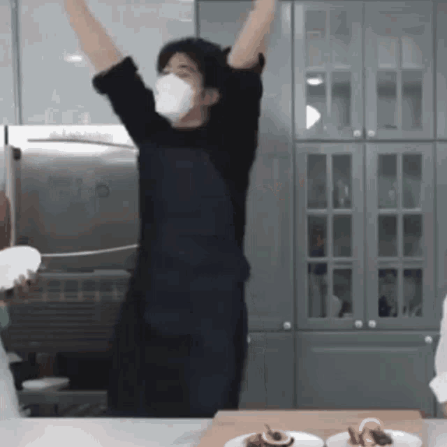 a man wearing a mask is dancing in a kitchen .