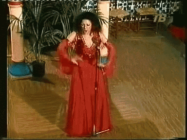 a woman in a red dress singing into a microphone with tb on the bottom right