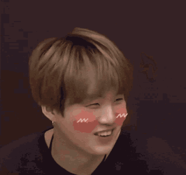 a young man with a pink heart on his cheek is smiling and holding a piece of paper
