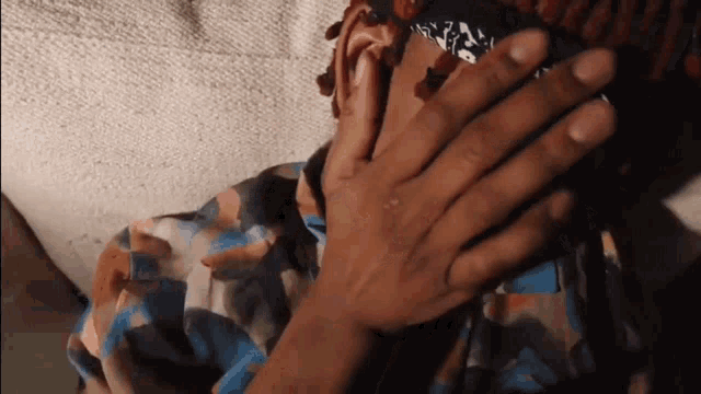 a close up of a person 's hand with a bandana on their head that says ' a ' on it