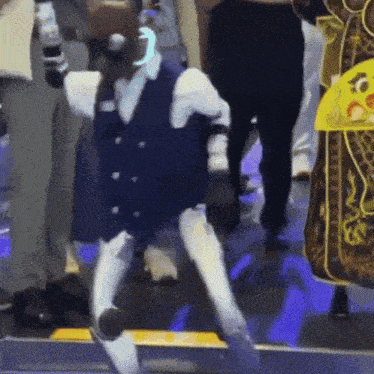 a robot in a blue vest and white pants is walking