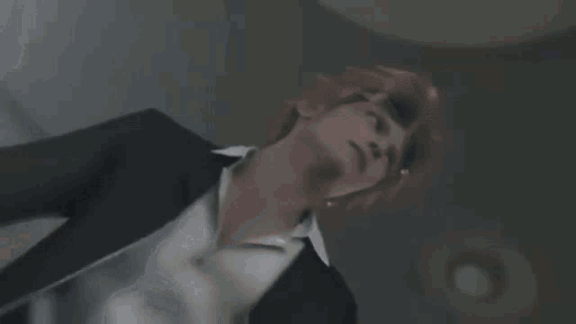 a person with red hair is standing in a dark room with a gun in their hand .
