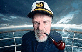 a captain is smoking a pipe on a boat .