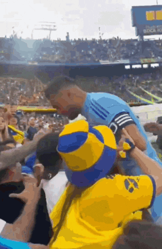 a soccer player is being lifted into the air by a fan in a crowd at a stadium .
