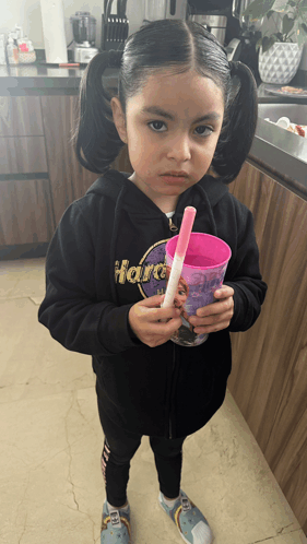 a little girl wearing a hard rock sweatshirt is holding a cup