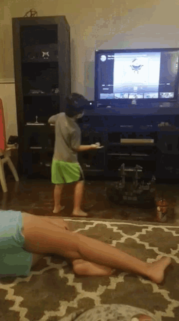 a boy playing a video game in front of a television with the letter x on it