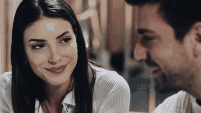 a man and woman are looking at each other and the woman is smiling