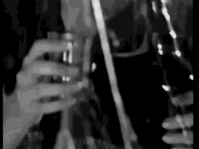 a black and white photo of a person holding a glass of alcohol .