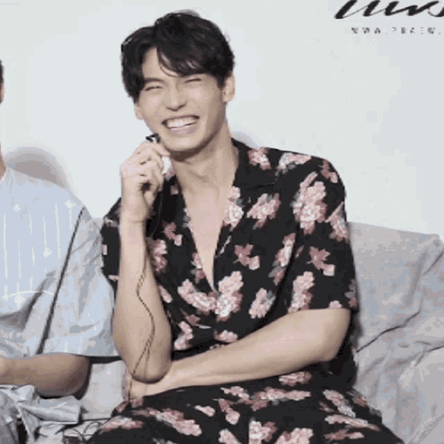 a man wearing a floral shirt is smiling while holding a microphone