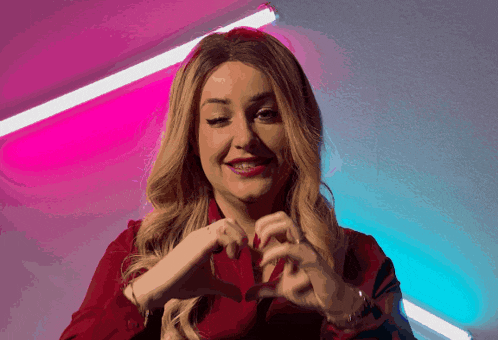 a woman is making a heart with her hands