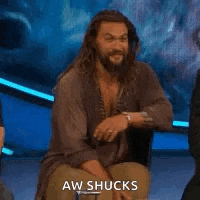a man with a beard is sitting in a chair on a stage and says aw shucks .