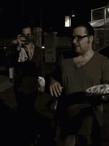 a man in a black shirt with a shark on it is getting a pie in his face
