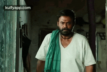 a man with a beard and a green towel around his neck is standing in a doorway .