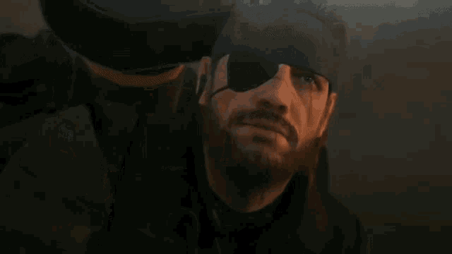 a man with a beard wearing an eye patch looks at the camera