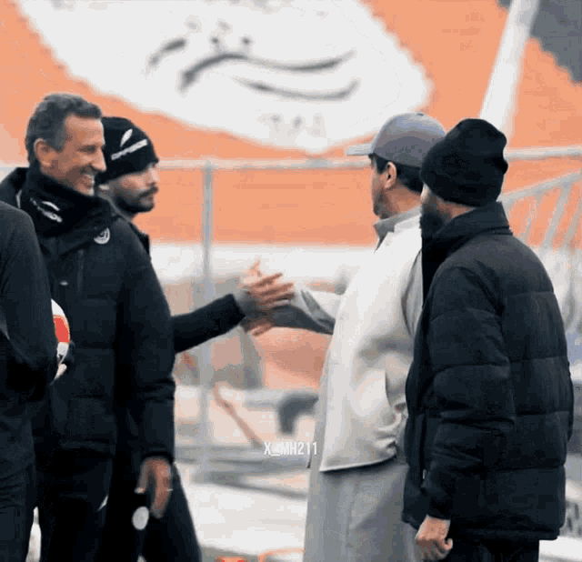 a man in a purple hat shakes hands with two other men
