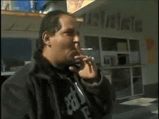 a man smoking a cigarette in front of a building that says ' australian '