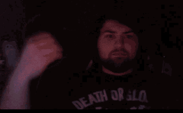 a man with a beard wearing a black shirt that says death or all