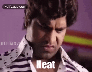 a man in a striped shirt is making a funny face and says heat .
