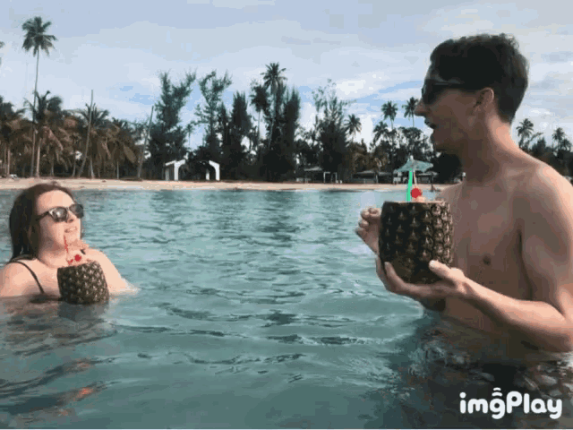 a man is holding a pineapple in the water next to a woman