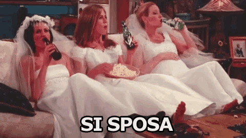 three women in wedding dresses are sitting on a couch drinking beer and popcorn .