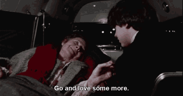 a man is talking to an elderly woman who is laying in the back of a bus and the words go and love some more are visible