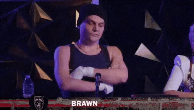 a man with his arms crossed has the name brawn on the screen behind him