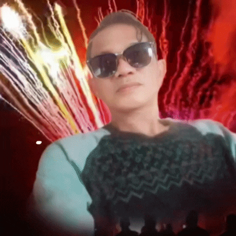 a man wearing sunglasses stands in front of a firework display