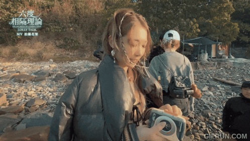 a girl is holding a camera and the website gifrun.com is in the corner