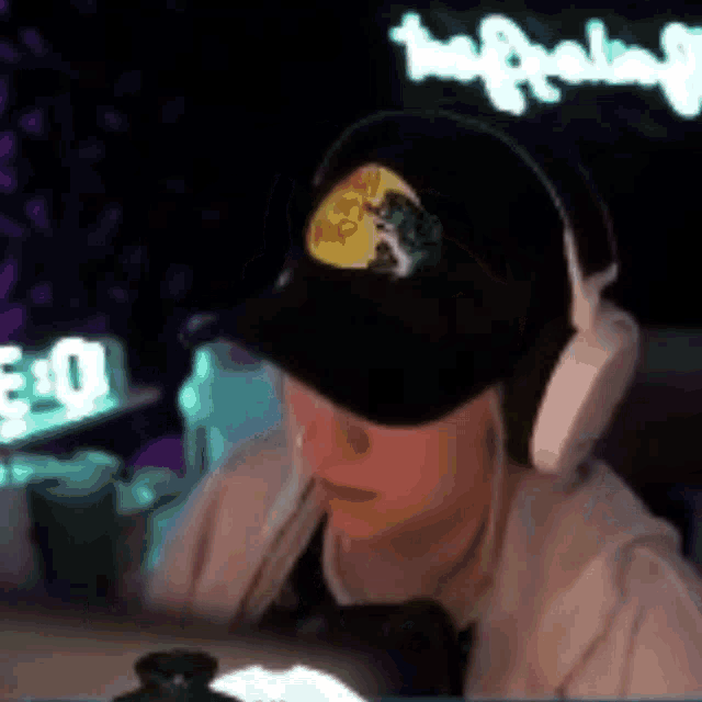 a woman wearing headphones and a hat is sitting in front of a computer screen .